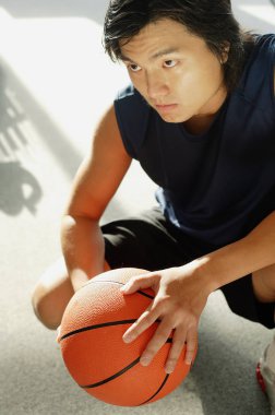 Çömelmiş, basketbol tutan adam