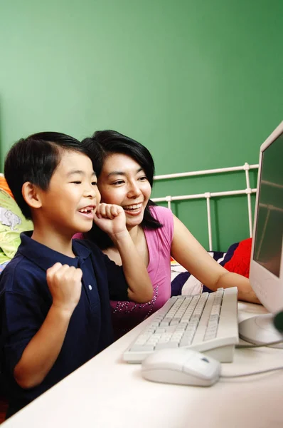 Mutter und Sohn schauen lächelnd auf den Computer — Stockfoto