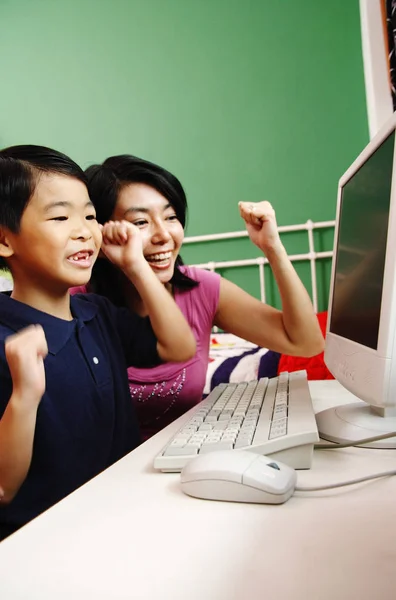 Mutter und Sohn schauen auf den Computer, lächeln, machen Fäuste — Stockfoto