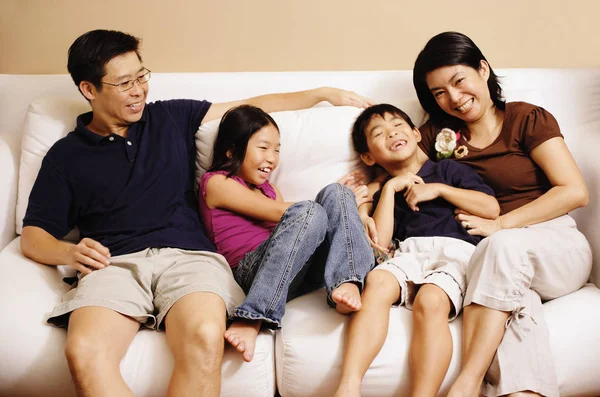 Family of four on sofa — Stock Photo, Image