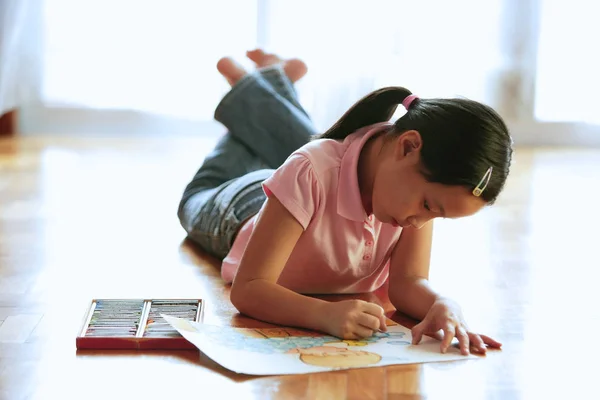 Meisje liggend op de vloer, met papier en kleurpotloden — Stockfoto