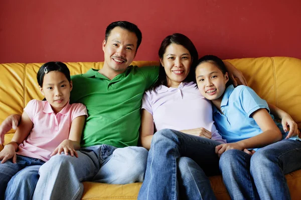 Família de quatro pessoas sentadas no sofá — Fotografia de Stock