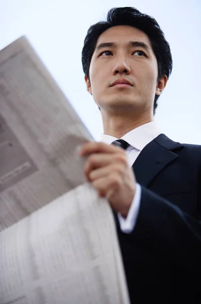 Empresario con periódico, mirando hacia otro lado — Foto de Stock