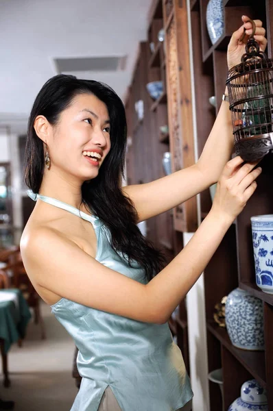 Mujer en tienda mirando la jaula de los pájaros — Foto de Stock