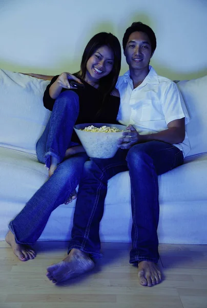 Пара на диване смотрит телевизор с попкорном — стоковое фото