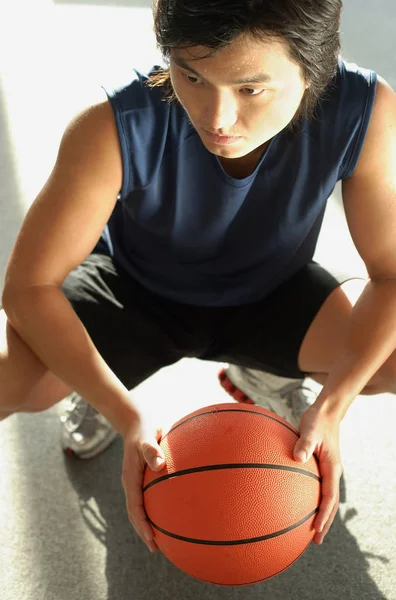 Homem agachado, segurando basquete — Fotografia de Stock