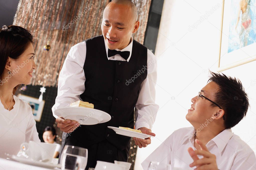 Waiter serving plates of dessert  