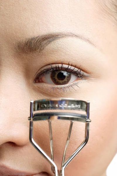 Young woman using eyelash curler