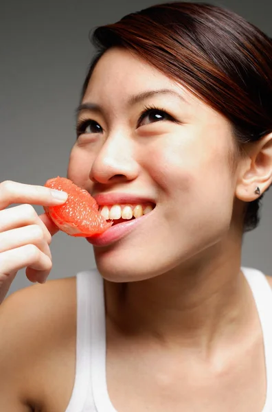 Mulher comendo laranja fatia — Fotografia de Stock