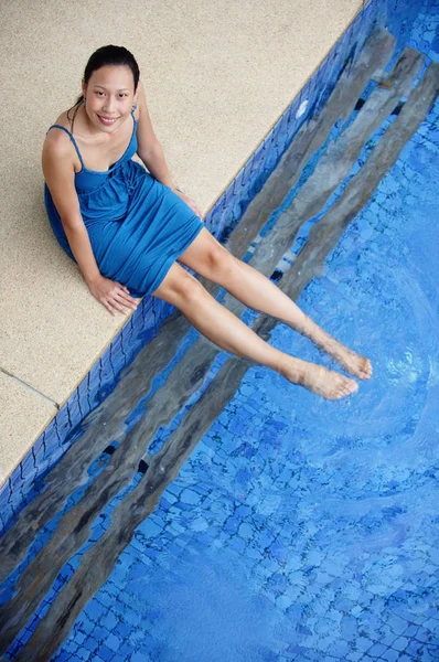 Mujer sentada junto a la piscina — Foto de Stock