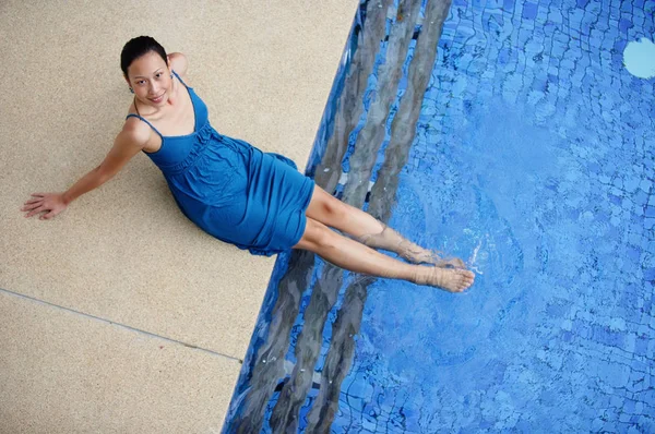 Mujer sentada junto a la piscina — Foto de Stock