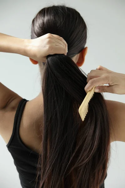 Mujer peinándose el pelo largo — Foto de Stock