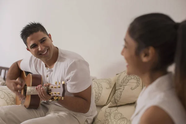 Чоловік грає на гітарі і дивиться на жінку — стокове фото