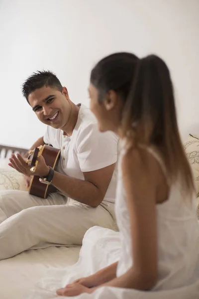 Чоловік грає на гітарі і дивиться на жінку — стокове фото