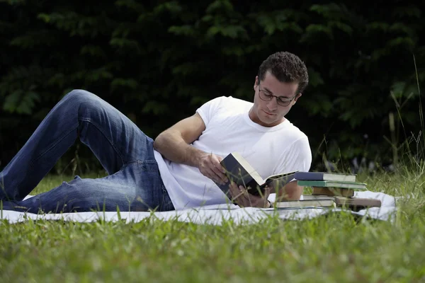 Homem com livros na grama — Fotografia de Stock