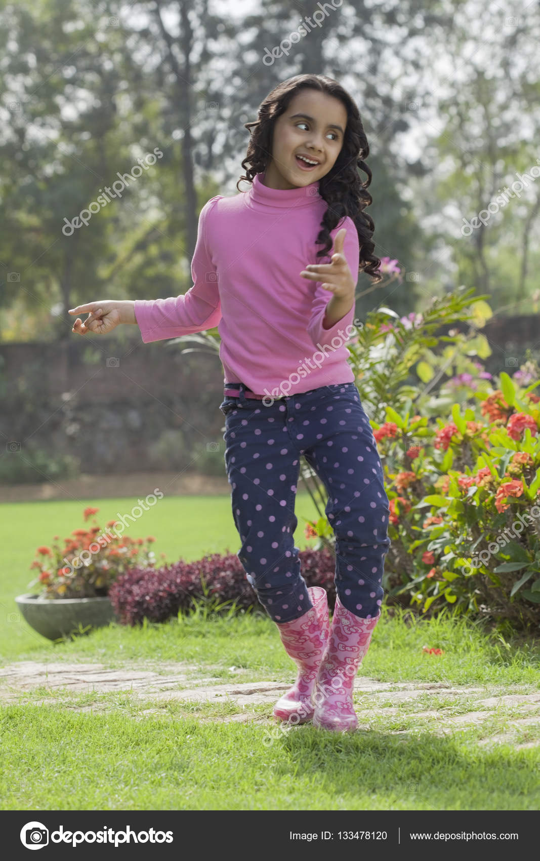 Girl in rubber boots dancing in garden 