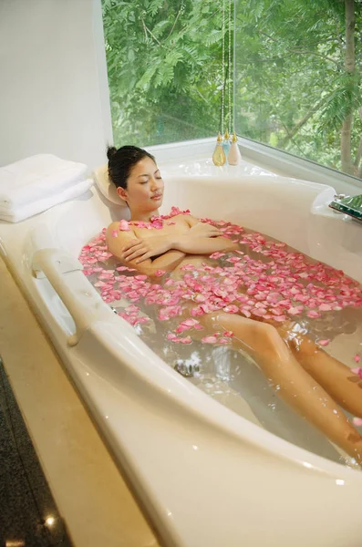 Mujer en bañera, flores flotando — Foto de Stock