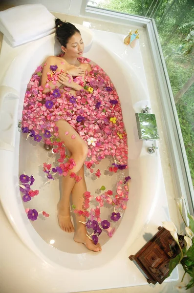 Женщина в ванной, цветы плавают — стоковое фото