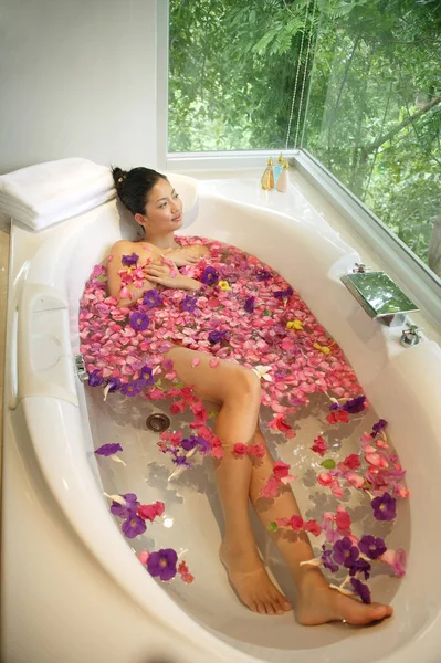 Женщина в ванной, цветы плавают — стоковое фото