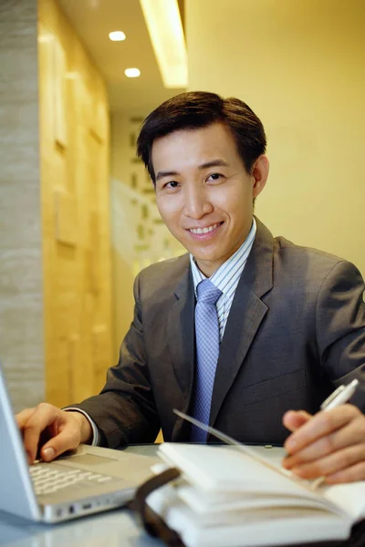 Бизнесмен с открытым ноутбуком на столе — стоковое фото