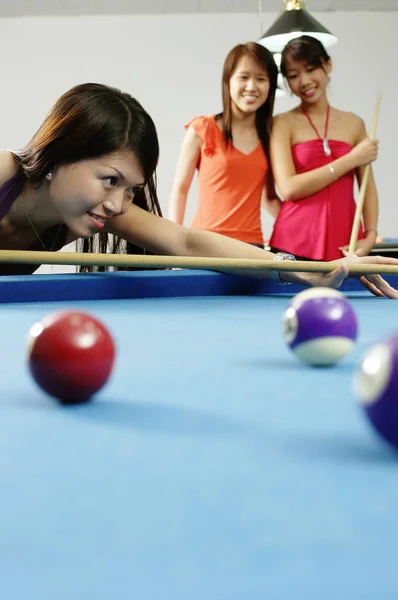 Vrouw met pool cue, pogend, vrouwen kijken op de achtergrond — Stockfoto