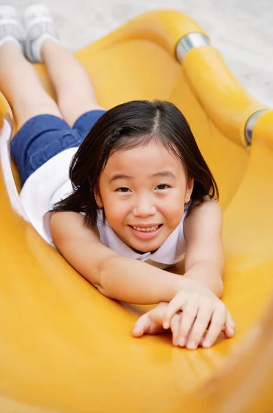 Menina no slide amarelo — Fotografia de Stock