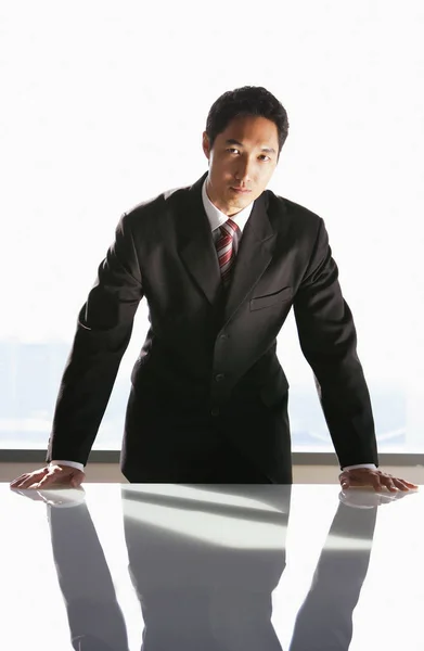 Бизнесмен, опирающийся на стол — стоковое фото