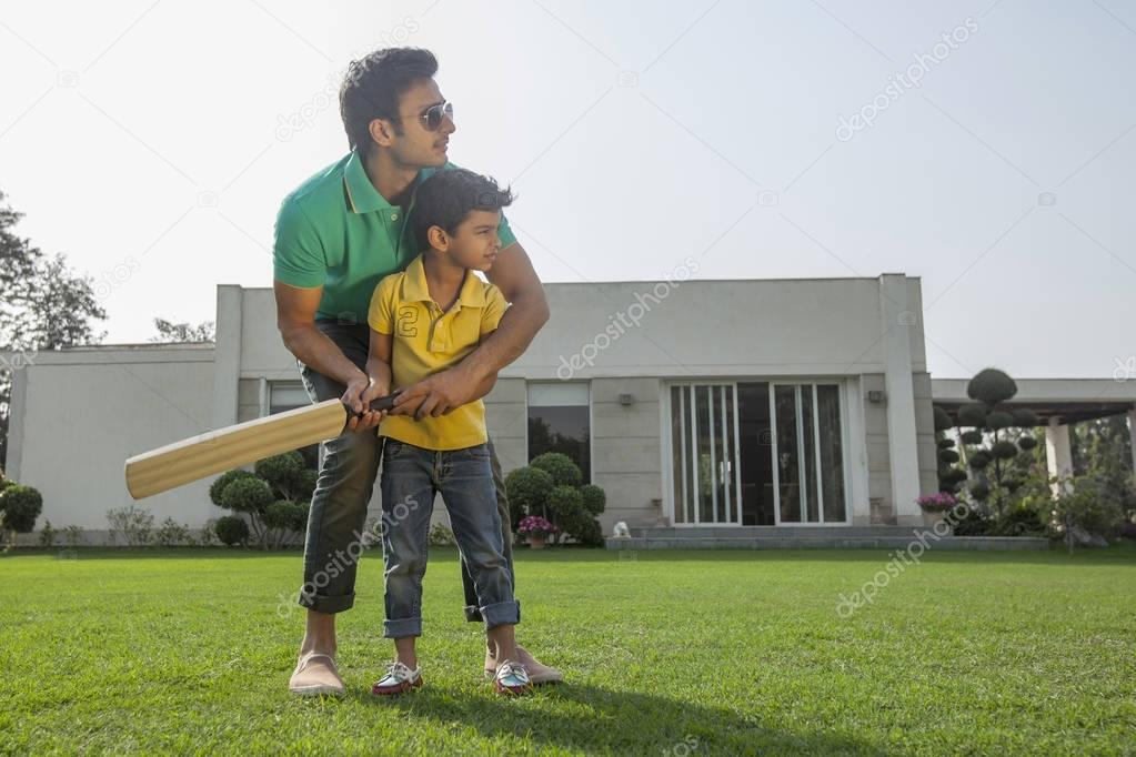 boy play cricket with father
