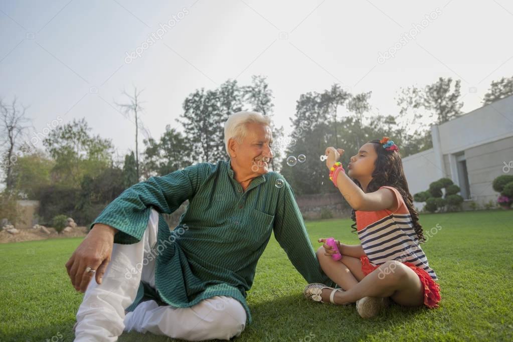 girl blowing bubbles with grandfather
