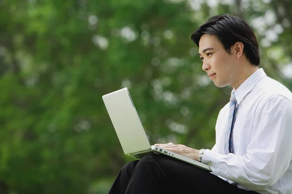 Uomo d'affari in parco con computer portatile — Foto Stock