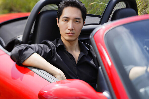 Man sitting in red convertible car