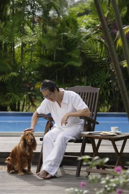 Yüzme havuzunun kenarında oturan olgun adam