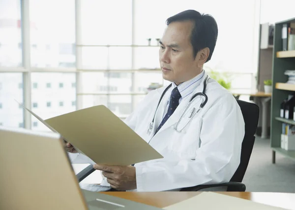 Lekarz w biurze, patrząc na folder — Zdjęcie stockowe