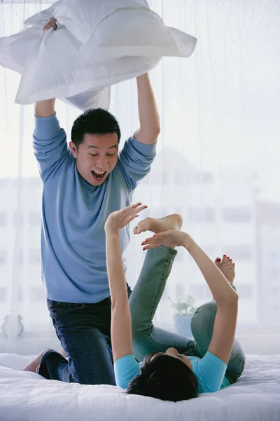 Pareja en dormitorio teniendo pelea de almohadas —  Fotos de Stock