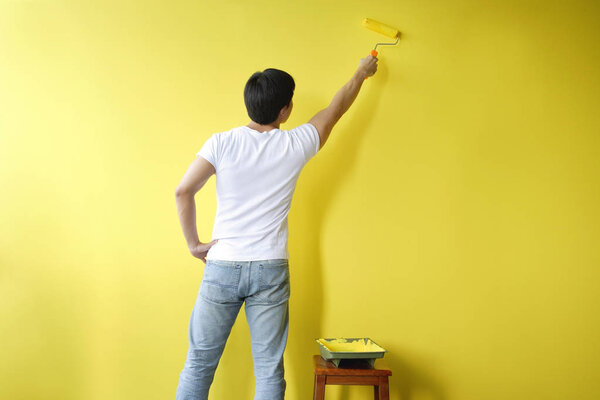 Man painting wall yellow