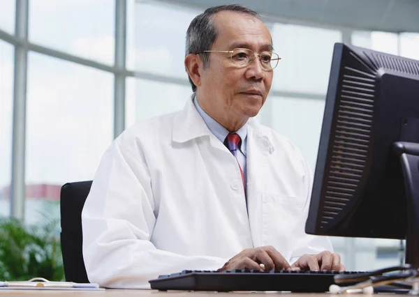 Médico no escritório, usando computador desktop — Fotografia de Stock