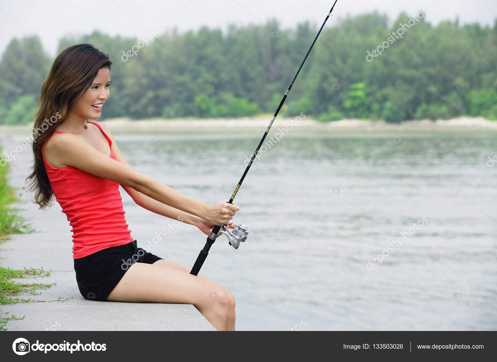 Girl's hand holding fishing rod and reel Stock Photo - Alamy