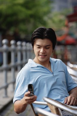 Adam açık havada, cep telefonu, kullanarak oturan kısa mesaj