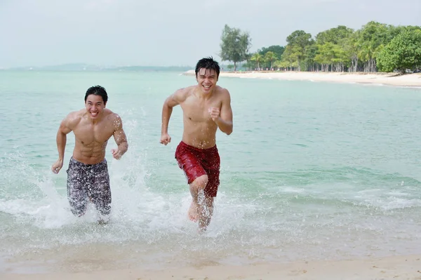 Άνδρες που τρέχουν κατά μήκος της παραλίας — Φωτογραφία Αρχείου