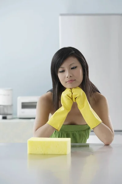 Mulher na cozinha, olhando para a esponja — Fotografia de Stock