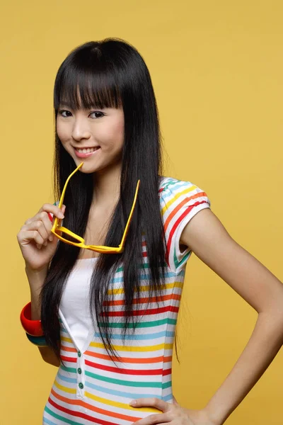 Young woman holding yellow sunglasses — Stock Photo, Image