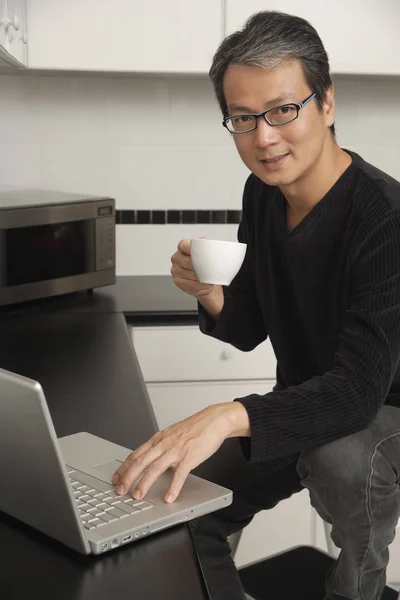 Mannen i köket med laptop — Stockfoto