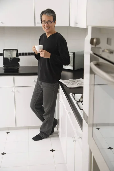 Man in kitchen, leaning on counter