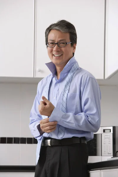 Homem na cozinha, abotoando sua camisa e gravata solta em torno do pescoço . — Fotografia de Stock