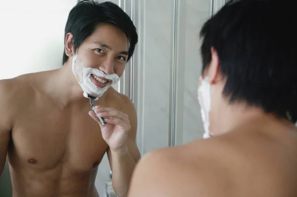 Мужчина смотрит в зеркало, бреется — стоковое фото