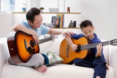Baba oğul gitar çalıyor.
