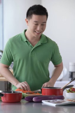 Adam mutfakta yemek pişiriyor.