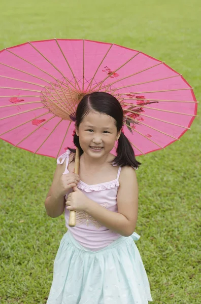 Девушка с розовым бумажным зонтиком — стоковое фото