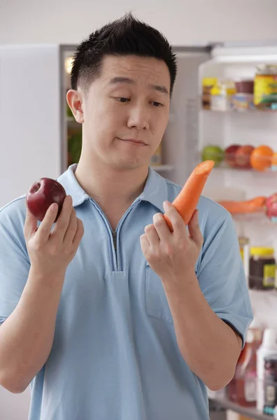 Man holding apple and carrot