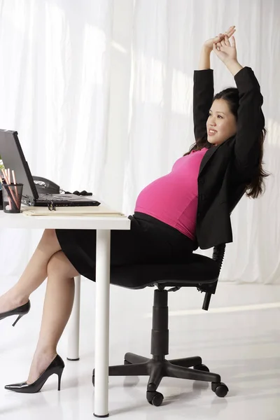 Zwangere zakenvrouw bij Bureau uitrekken — Stockfoto